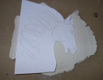 The head was made from a seperate sheet of clay. I placed my drawing on top and cut around it.